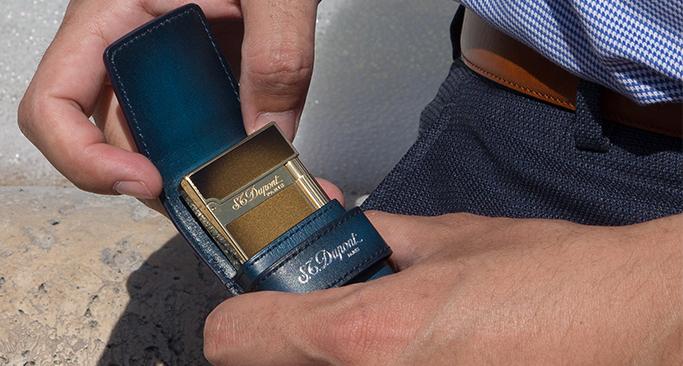 S.T. Dupont atelier lighter with bronze lacquer being placed into a blue leather lighter case.