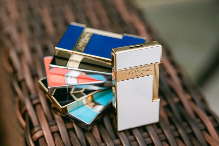 S.T. Dupont premium jet Slimmy lighter in white and gold, blue and gold, black and gold, coral and gold, black and palladium, and light blue and palladium models.