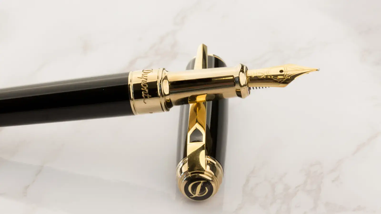S.T. Dupont New Line D fountain pen with black lacquer and gold finish atop white marble