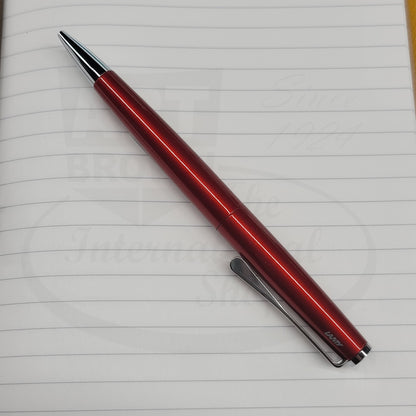 Lamy Studio piano red ballpoint pen sitting on a lined notebook.