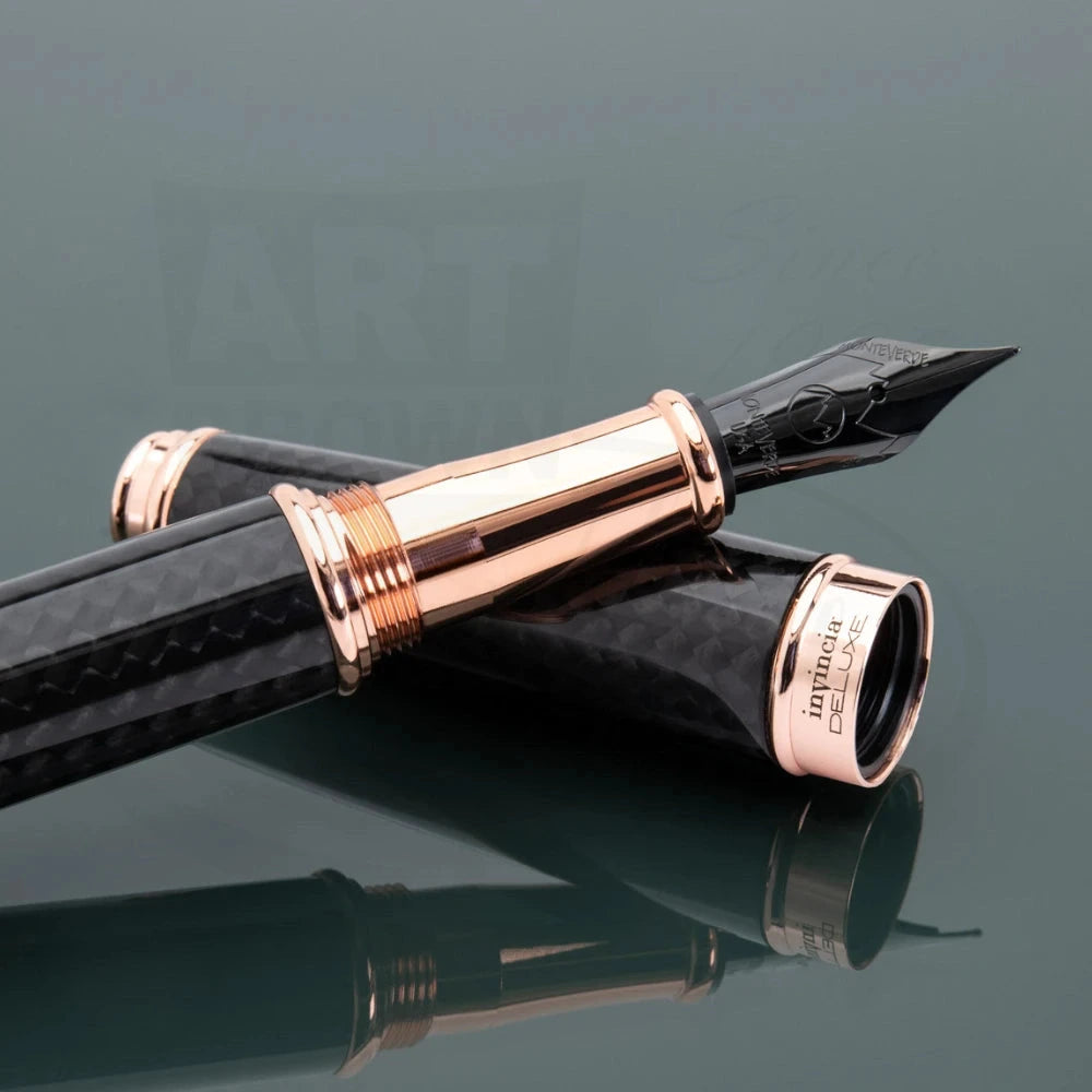 Monteverde Invincia Deluxe ballpoint pen with carbon fiber barrel and rose gold finishes displaying the nib on a reflective green background.