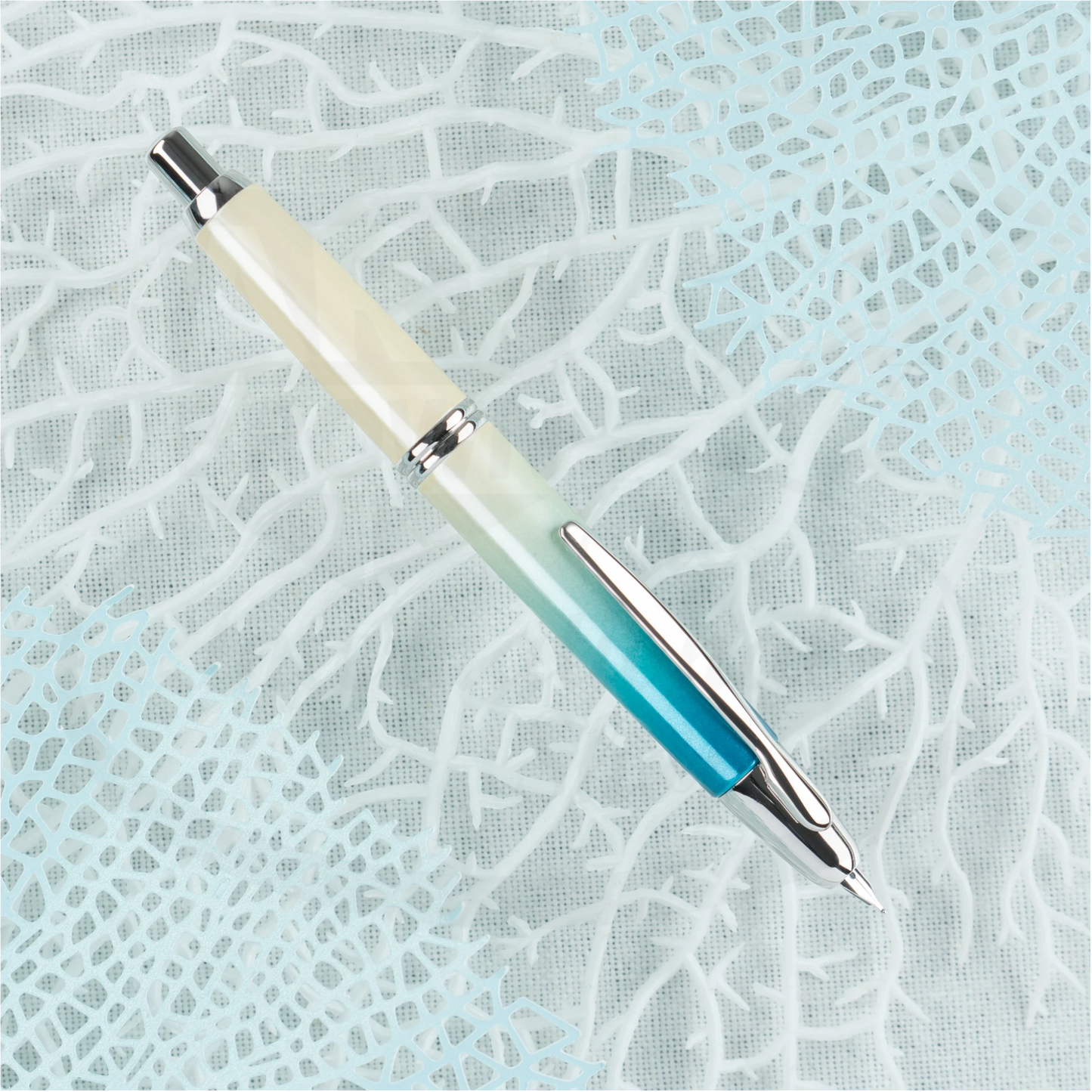 Pilot Vanishing Point 2024 Limited Edition fountain pen in blue to white ombre finish with rhodium accents, photographed on a textured blue backdrop.